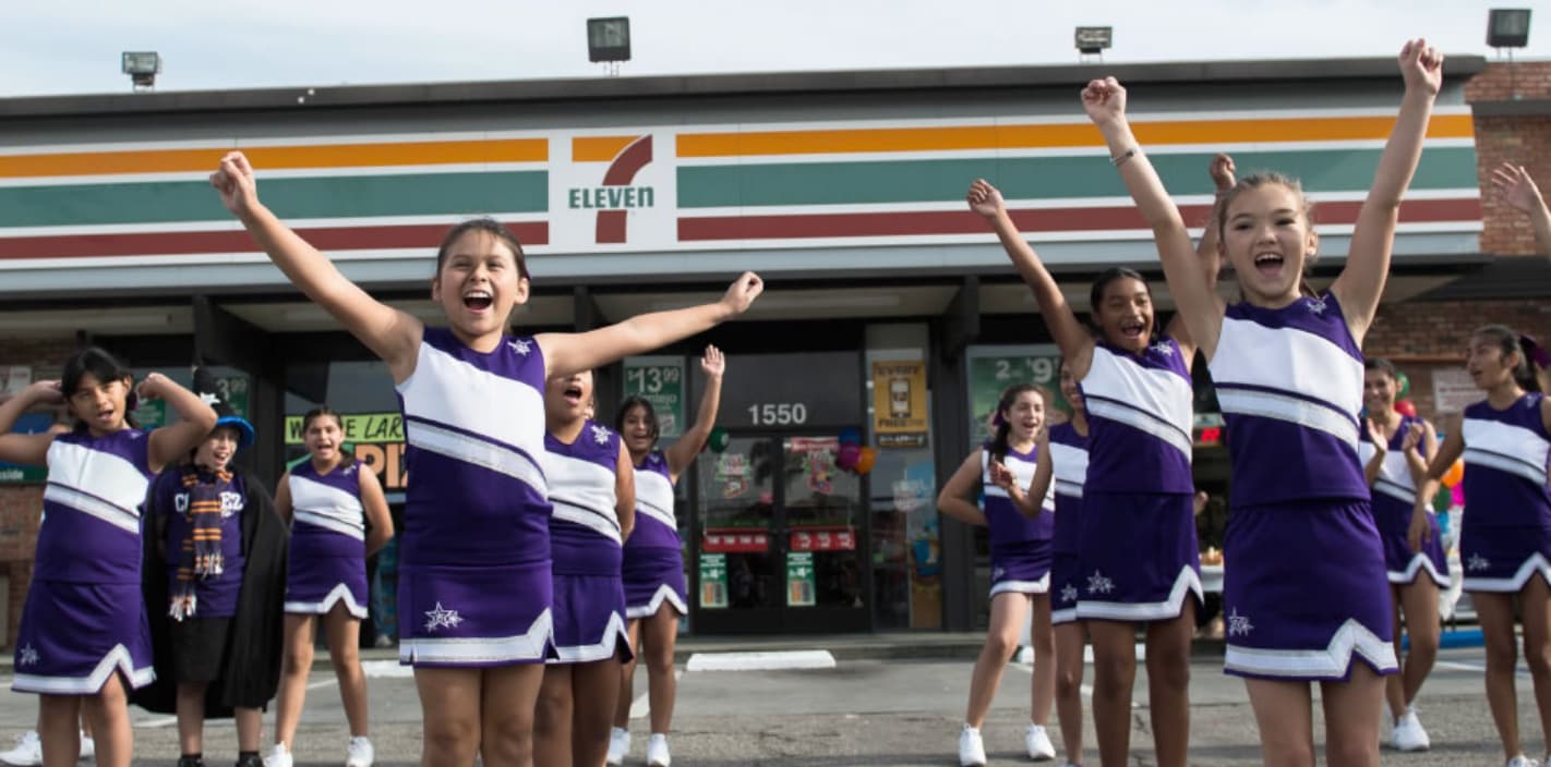 cheerleaders in front of a 7-Eleven store